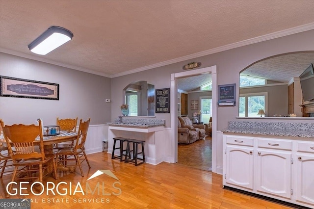 1088 New Rosedale Rd NE, Armuchee, GA 30105 - dining room with arched walkways, light wood-type flooring, a textured ceiling, a wainscoted wall, and crown molding