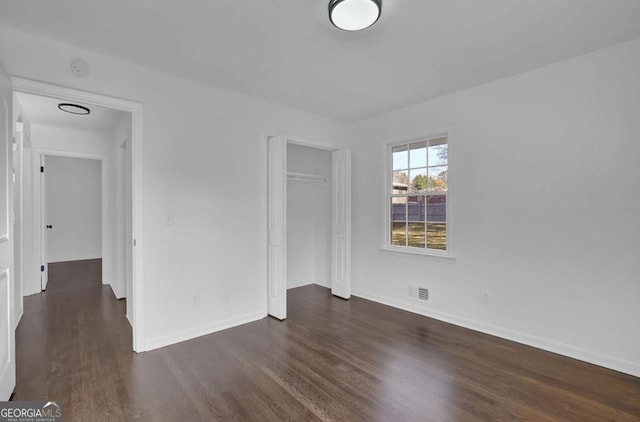 unfurnished bedroom featuring dark hardwood / wood-style floors and a closet