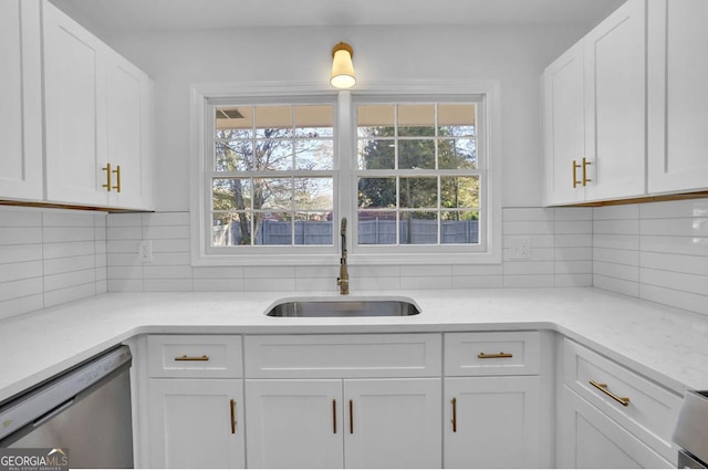 kitchen featuring dishwasher, white cabinets, sink, decorative backsplash, and light stone counters