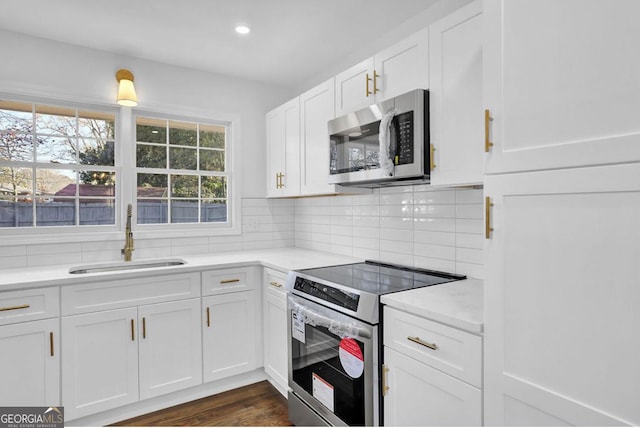 kitchen with decorative backsplash, appliances with stainless steel finishes, dark hardwood / wood-style flooring, sink, and white cabinetry