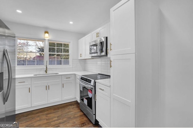 kitchen featuring backsplash, stainless steel appliances, sink, dark hardwood / wood-style floors, and white cabinetry