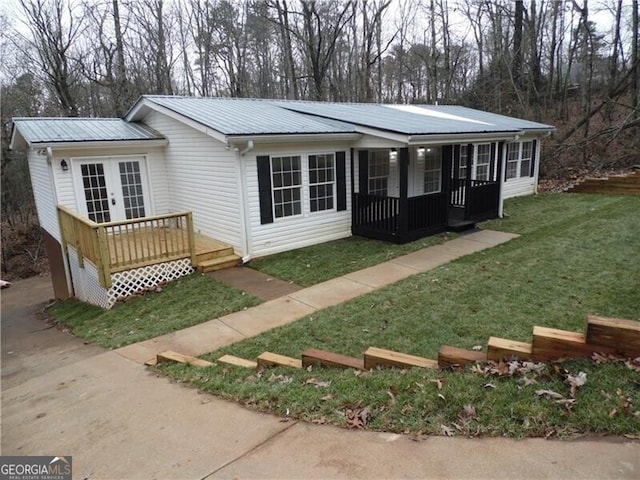 view of front of house featuring a wooden deck, french doors, a front lawn, and covered porch