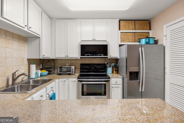 kitchen featuring backsplash, sink, light stone countertops, white cabinetry, and stainless steel appliances