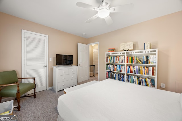 bedroom with ceiling fan, light carpet, and a closet