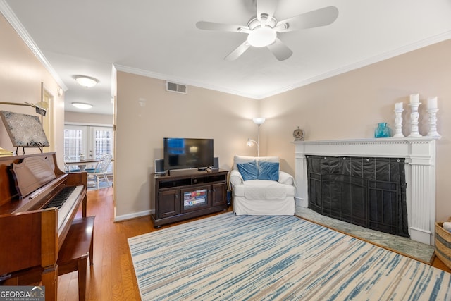 living room featuring crown molding, ceiling fan, and light wood-type flooring