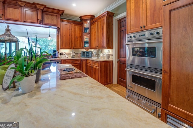 kitchen with light stone countertops, stainless steel double oven, light hardwood / wood-style floors, and ornamental molding