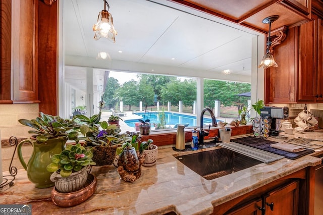 kitchen with light stone countertops, pendant lighting, tasteful backsplash, and sink