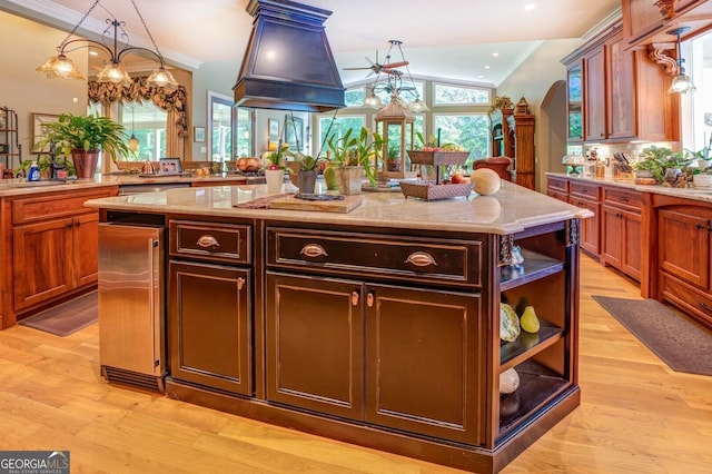 kitchen featuring a center island, light stone counters, crown molding, and light hardwood / wood-style flooring