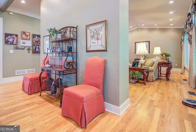 living area featuring light hardwood / wood-style floors, lofted ceiling, and ornamental molding