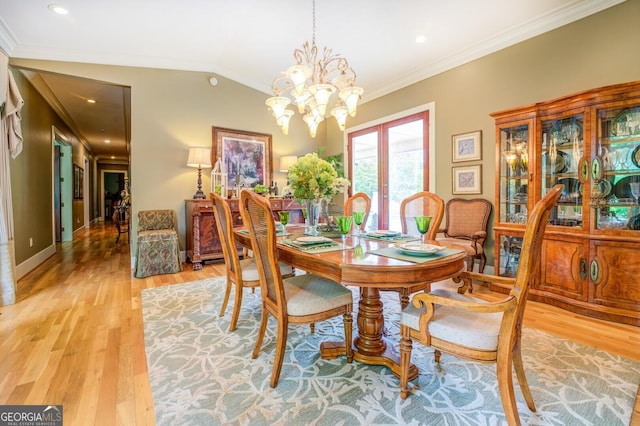 dining space with french doors, a notable chandelier, hardwood / wood-style floors, lofted ceiling, and ornamental molding