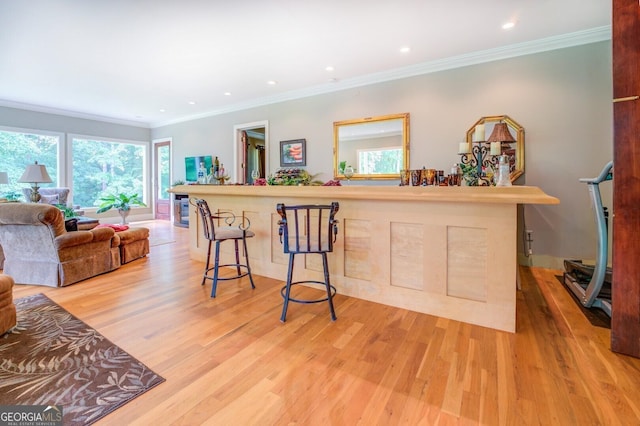 kitchen featuring a kitchen bar, crown molding, and light wood-type flooring