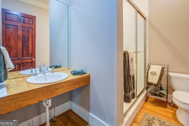 bathroom with toilet, wood-type flooring, crown molding, and walk in shower