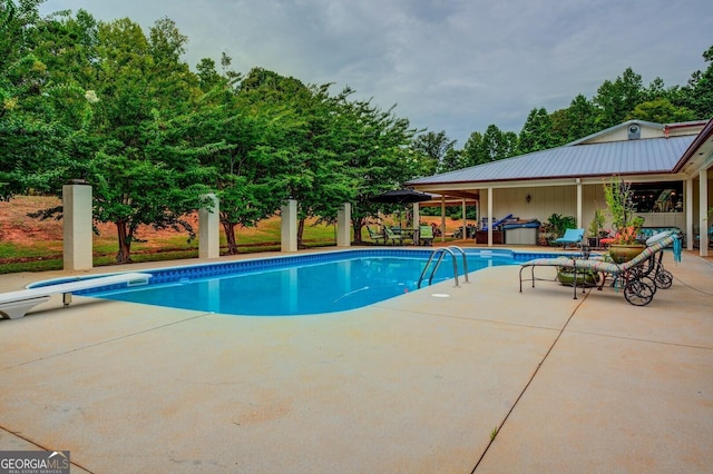 view of swimming pool with a jacuzzi, a patio, and a diving board