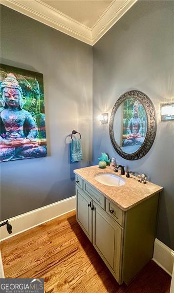 bathroom with wood-type flooring, vanity, and ornamental molding