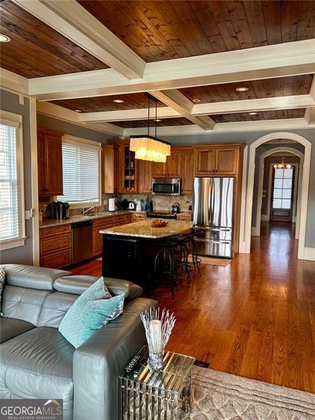 kitchen featuring light stone countertops, stainless steel appliances, decorative light fixtures, a center island, and a breakfast bar area