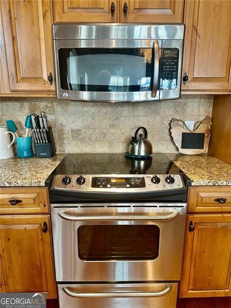 kitchen featuring decorative backsplash, light stone counters, and stainless steel appliances