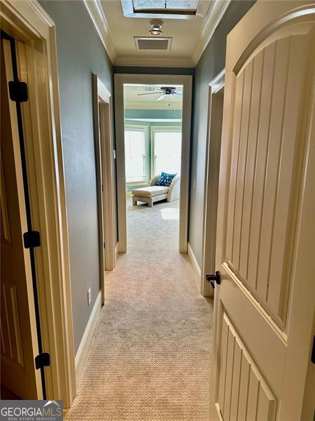 hallway with light colored carpet and ornamental molding