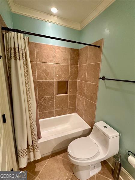 bathroom with tile patterned floors, toilet, ornamental molding, and shower / tub combo