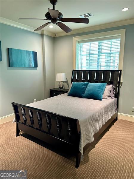 bedroom with ceiling fan, light carpet, and ornamental molding