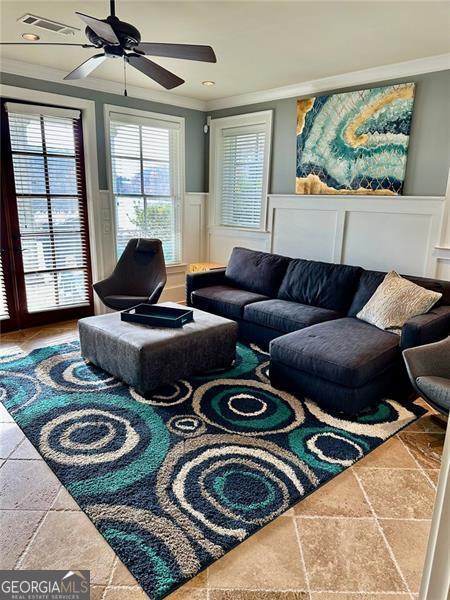 living room with ceiling fan and ornamental molding