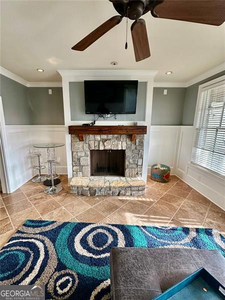 living room with ceiling fan, crown molding, and a fireplace