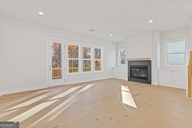 unfurnished living room featuring light hardwood / wood-style flooring and a tiled fireplace