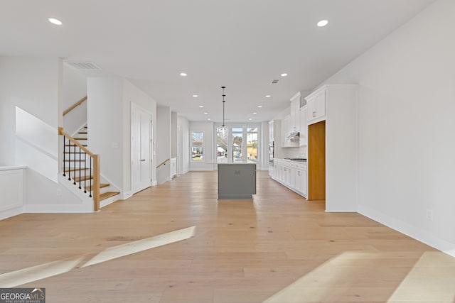 kitchen featuring a center island, white cabinets, pendant lighting, and light hardwood / wood-style floors