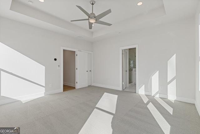 carpeted spare room featuring a raised ceiling and ceiling fan