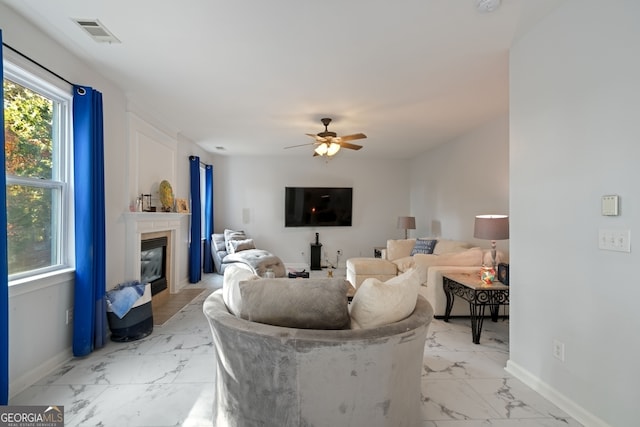 living room with a tiled fireplace and ceiling fan