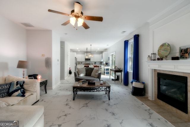 living room with ceiling fan and a tiled fireplace