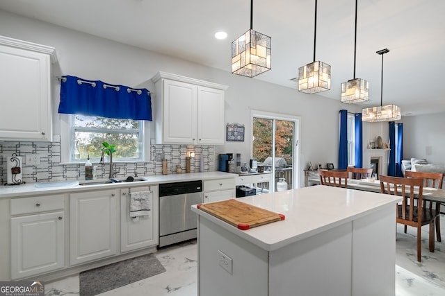 kitchen featuring hanging light fixtures, sink, white cabinets, and stainless steel dishwasher