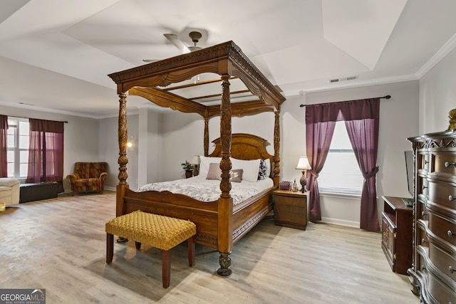 bedroom featuring ceiling fan, light hardwood / wood-style floors, ornamental molding, and a tray ceiling