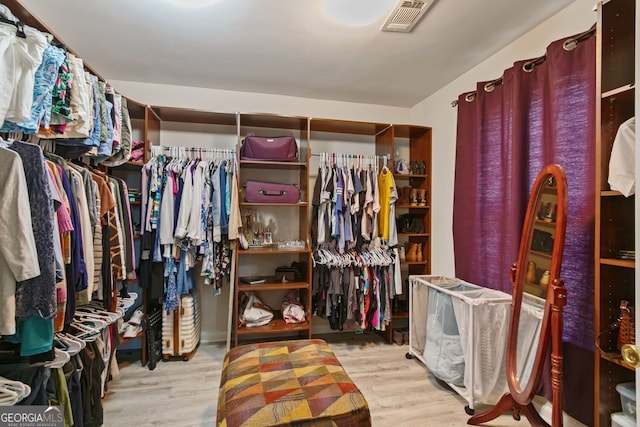 walk in closet with light hardwood / wood-style flooring