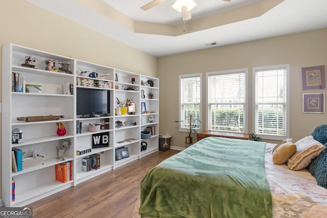 bedroom featuring a raised ceiling, ceiling fan, and wood-type flooring