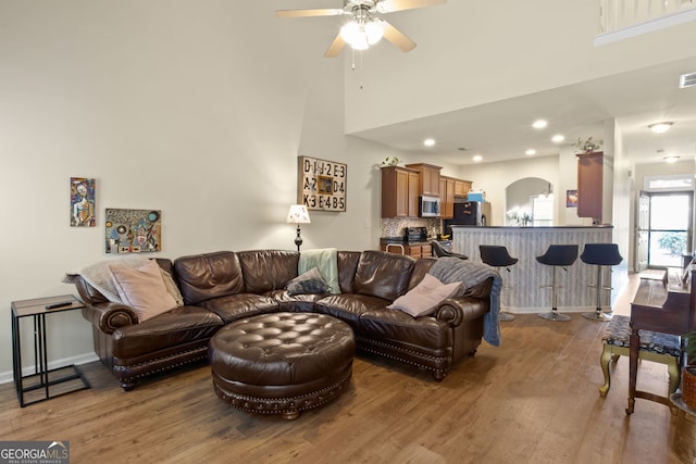 living room featuring ceiling fan, a towering ceiling, and hardwood / wood-style flooring