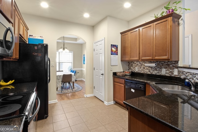 kitchen featuring sink, black appliances, dark stone countertops, a chandelier, and hanging light fixtures