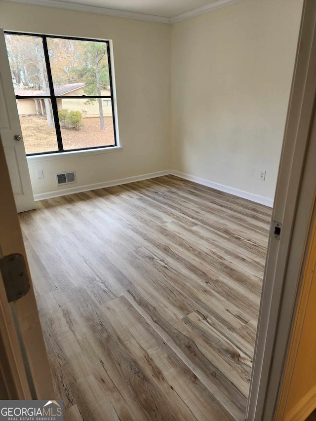 empty room with light hardwood / wood-style floors and ornamental molding