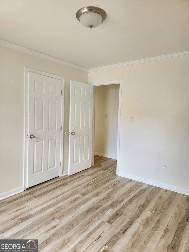 spare room featuring light wood-type flooring and ornamental molding