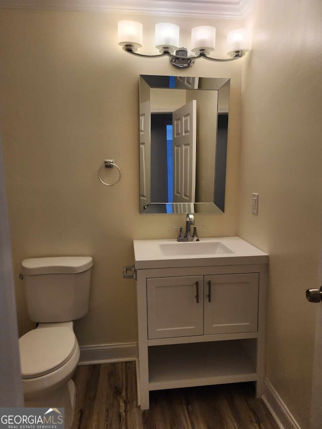 bathroom featuring crown molding, vanity, wood-type flooring, and toilet