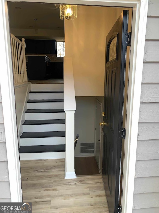 stairs featuring hardwood / wood-style floors and a notable chandelier