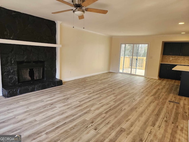 unfurnished living room featuring a fireplace, light wood-type flooring, ceiling fan, and ornamental molding