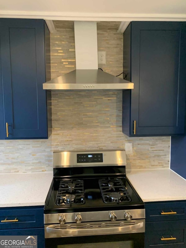 kitchen featuring gas range, backsplash, blue cabinets, and wall chimney exhaust hood