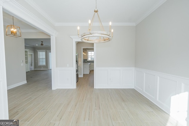 unfurnished dining area featuring light hardwood / wood-style flooring, crown molding, and a notable chandelier