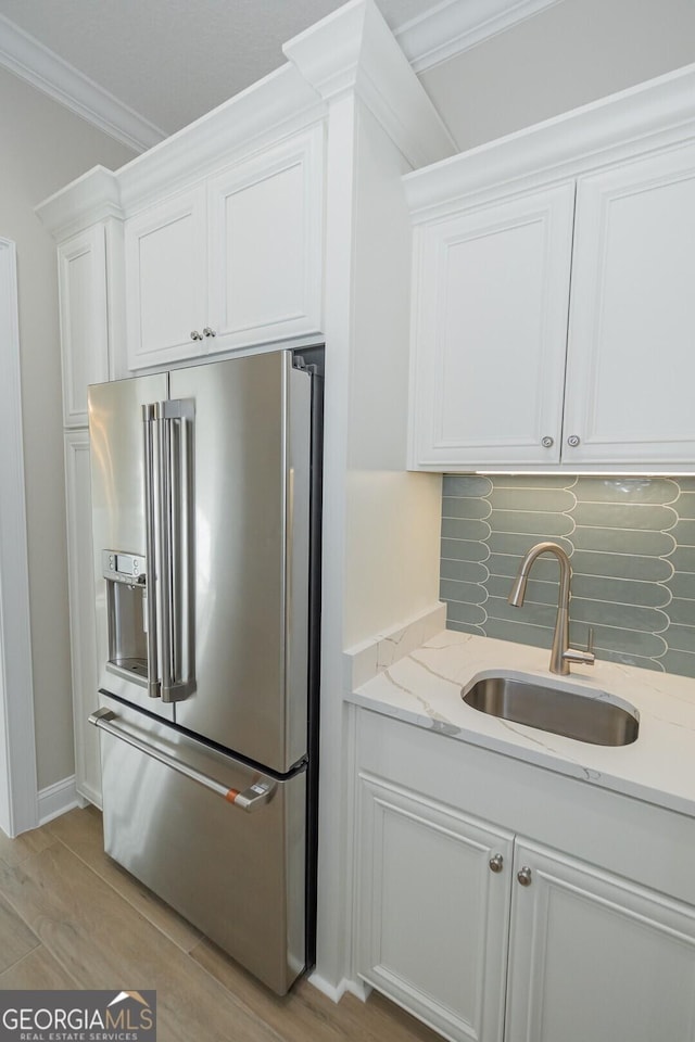 kitchen featuring white cabinetry, sink, light stone countertops, stainless steel fridge, and light wood-type flooring