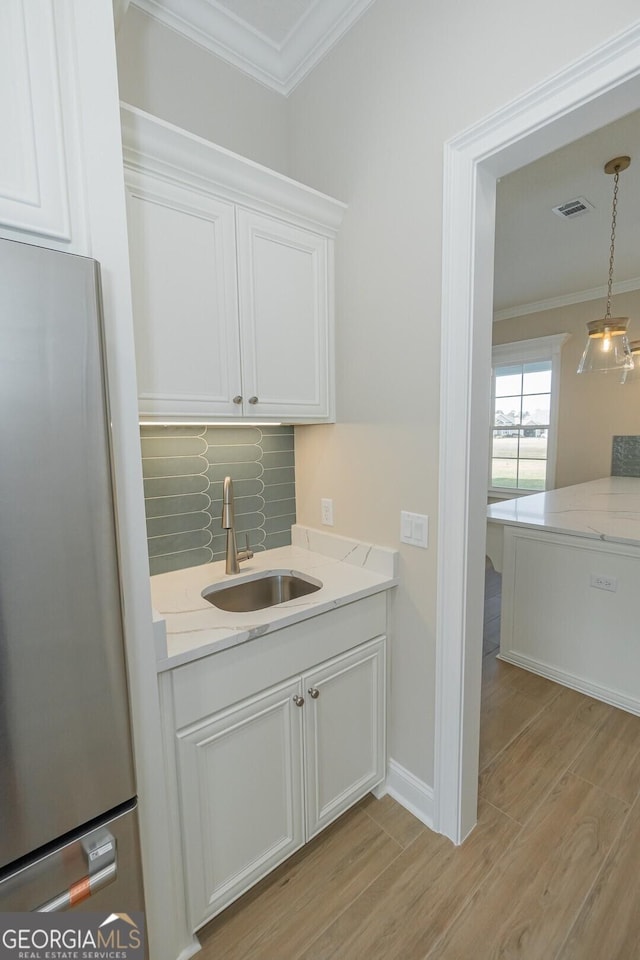 interior space featuring stainless steel refrigerator, white cabinetry, sink, and light hardwood / wood-style flooring