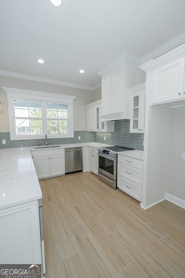 kitchen with appliances with stainless steel finishes, light stone counters, sink, light hardwood / wood-style flooring, and white cabinetry