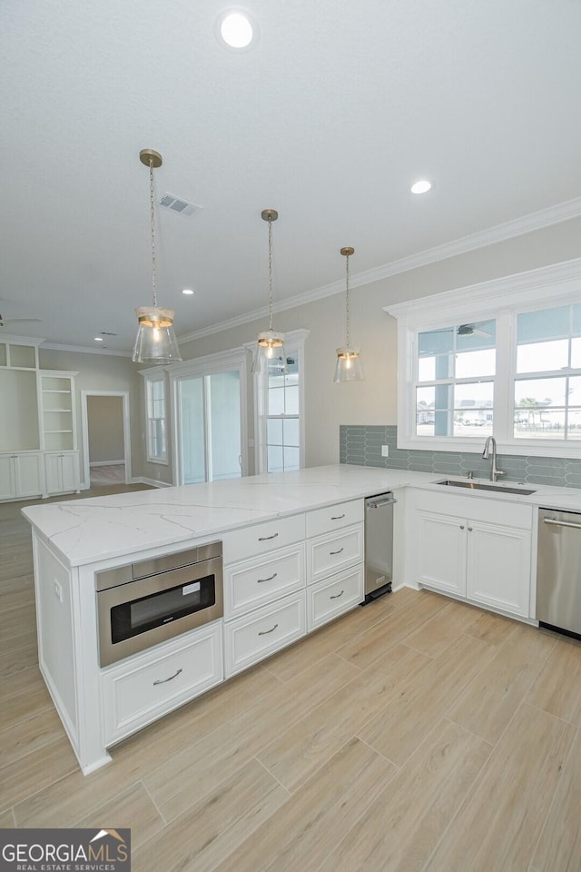 kitchen featuring sink, decorative light fixtures, light stone counters, white cabinetry, and stainless steel appliances