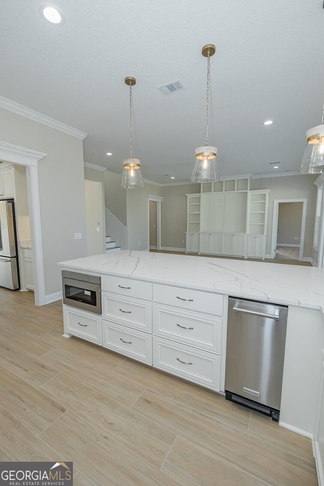 kitchen featuring appliances with stainless steel finishes, white cabinetry, light stone counters, and hanging light fixtures