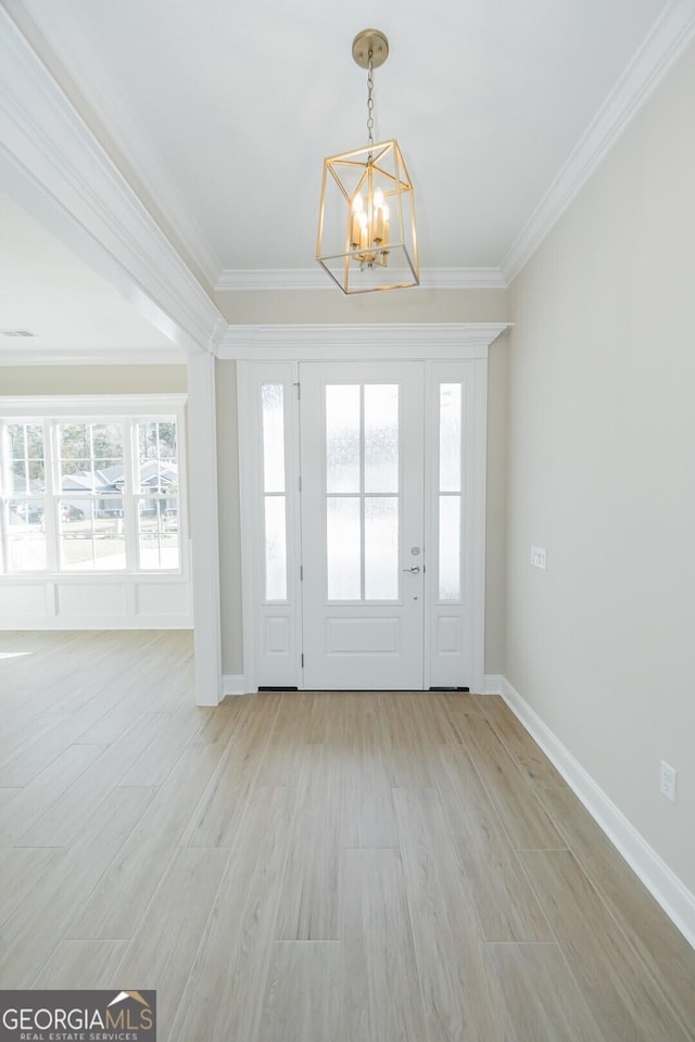 entrance foyer with crown molding, plenty of natural light, light hardwood / wood-style flooring, and an inviting chandelier