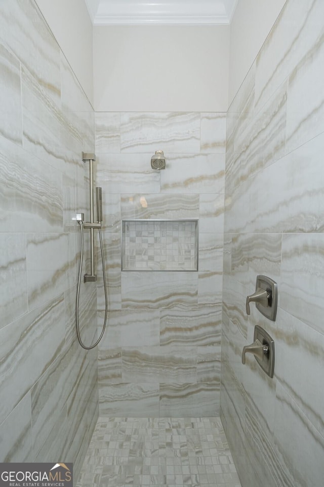 bathroom featuring a tile shower and crown molding